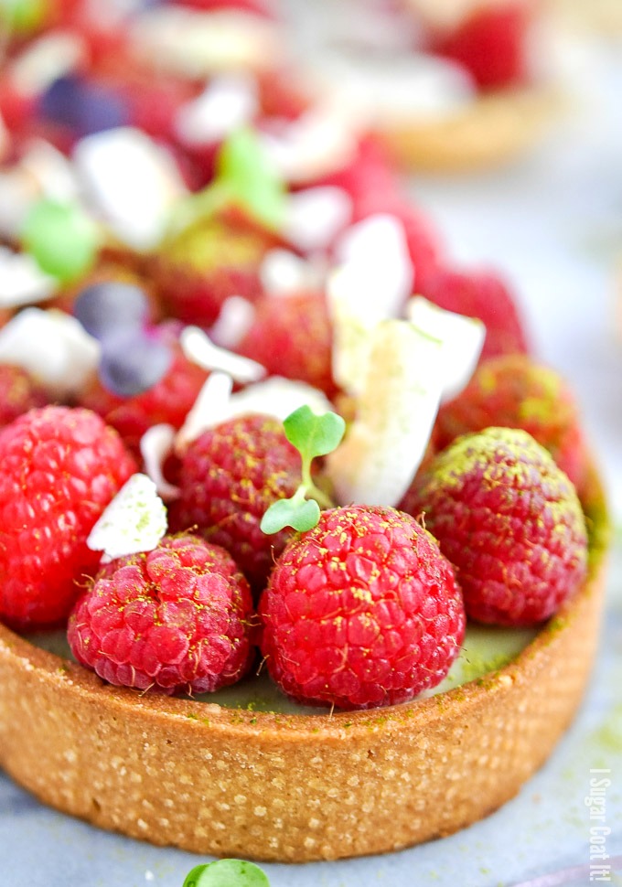 A delightful Coconut Matcha Ganache Tart with layers of silky green tea coconut ganache, raspberries and toasted coconut in a homemade sweet pastry.